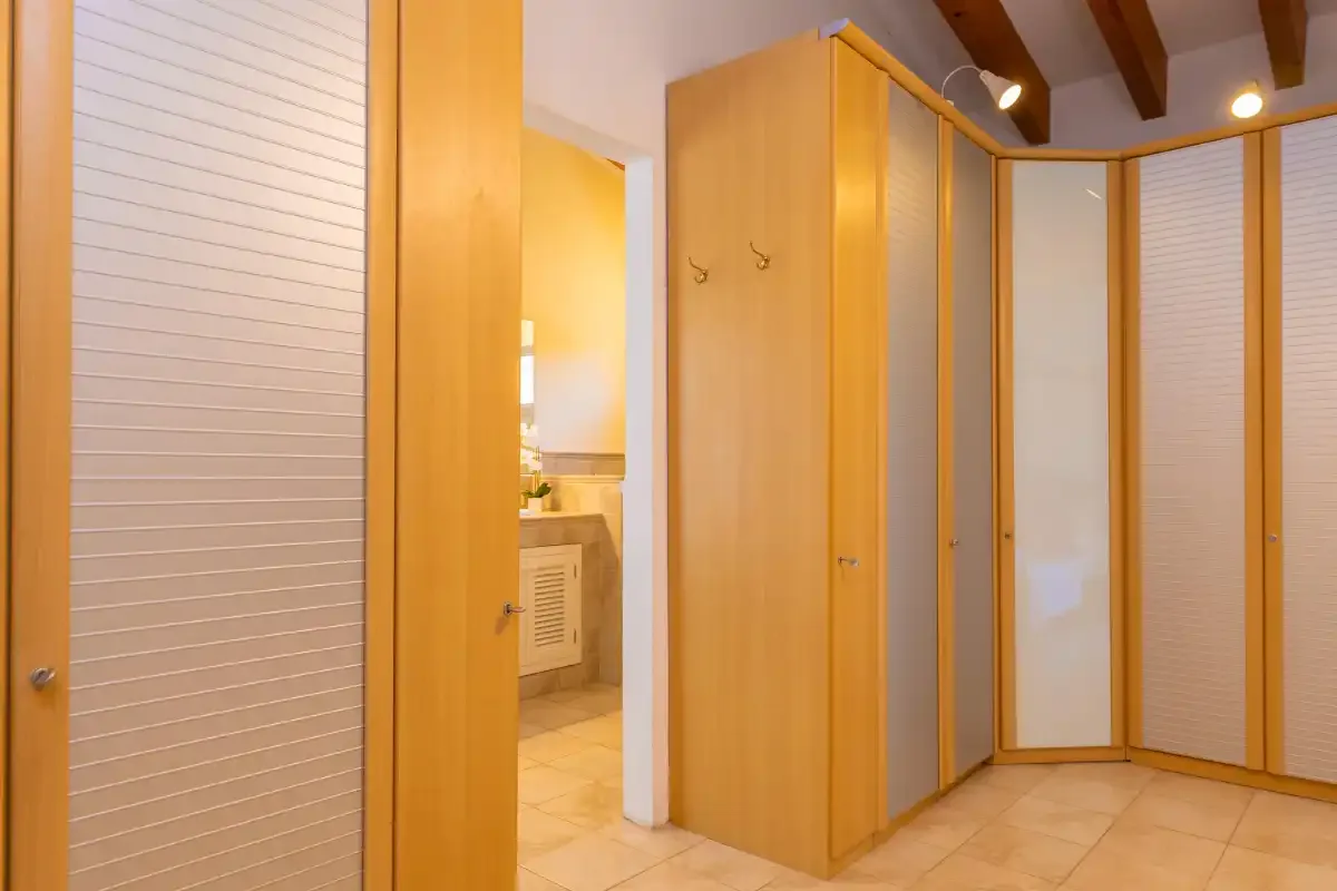 Vestidor con armarios de madera clara y suelo de baldosas.