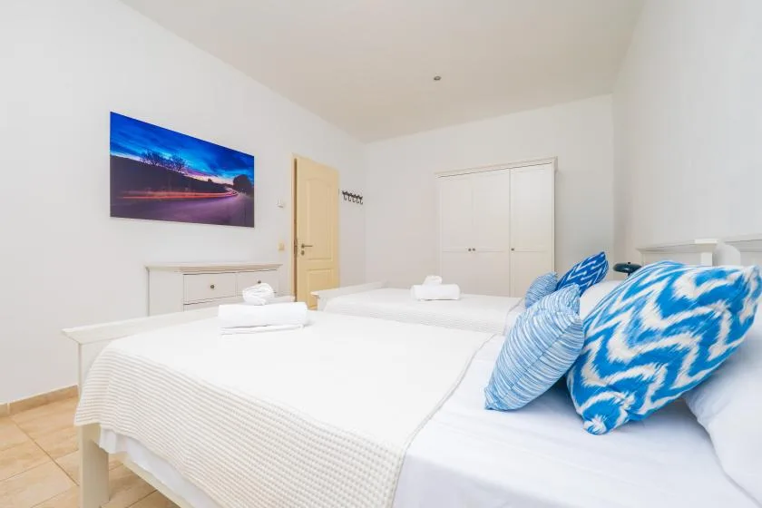 Un dormitorio luminoso con ropa de cama blanca y cojines azules estampados.