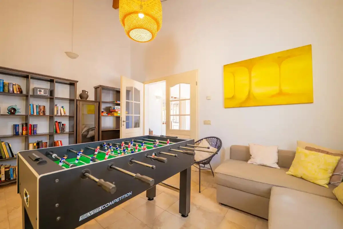 Una sala de juegos con futbolín, estanterías y asientos.