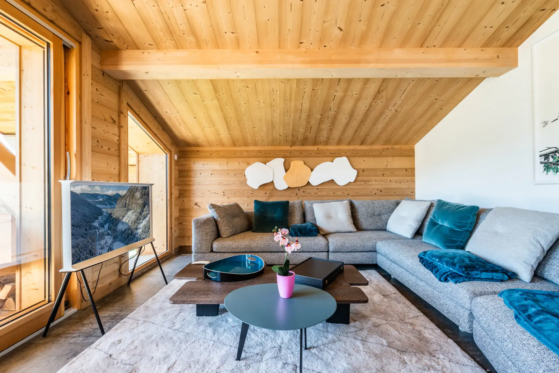 A living room with sectional seating, low tables, and wood-paneled walls.