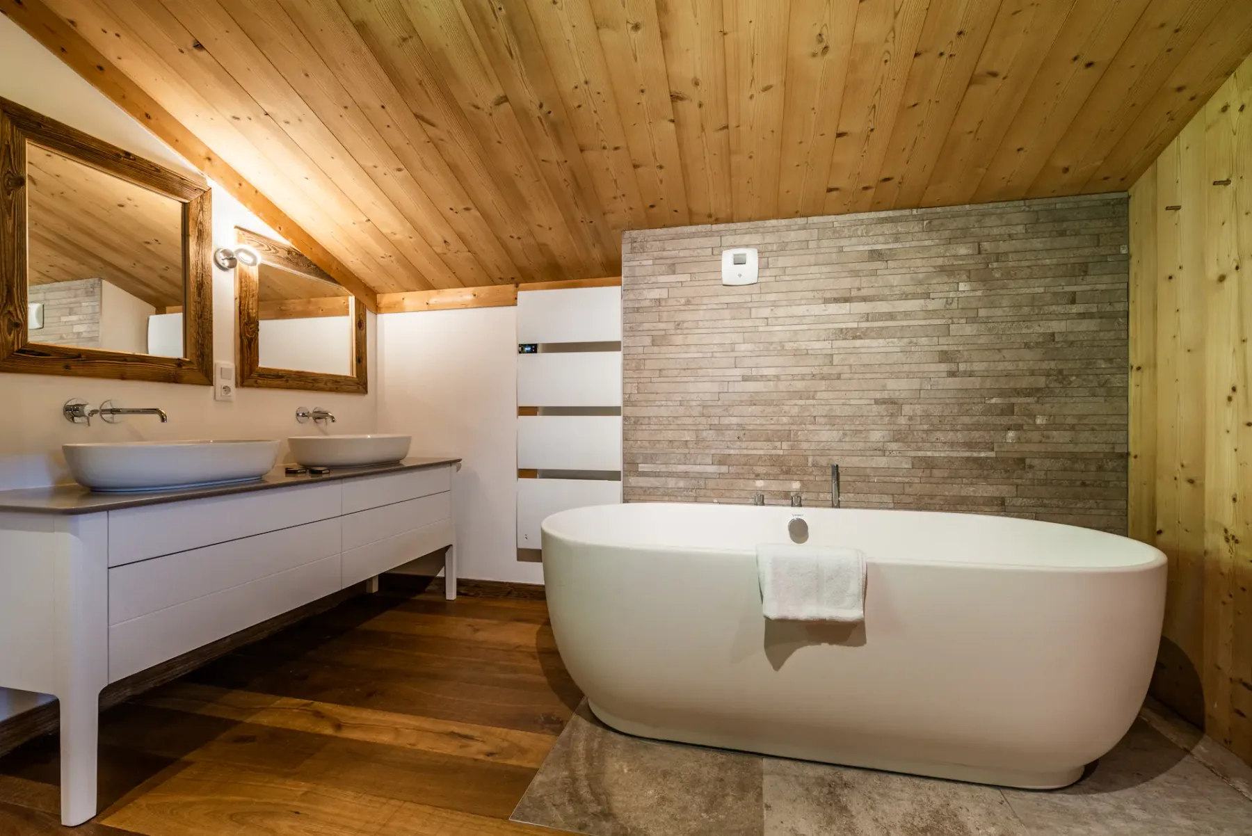 A bathroom with a freestanding bathtub, vanity, and wood-paneled ceiling.