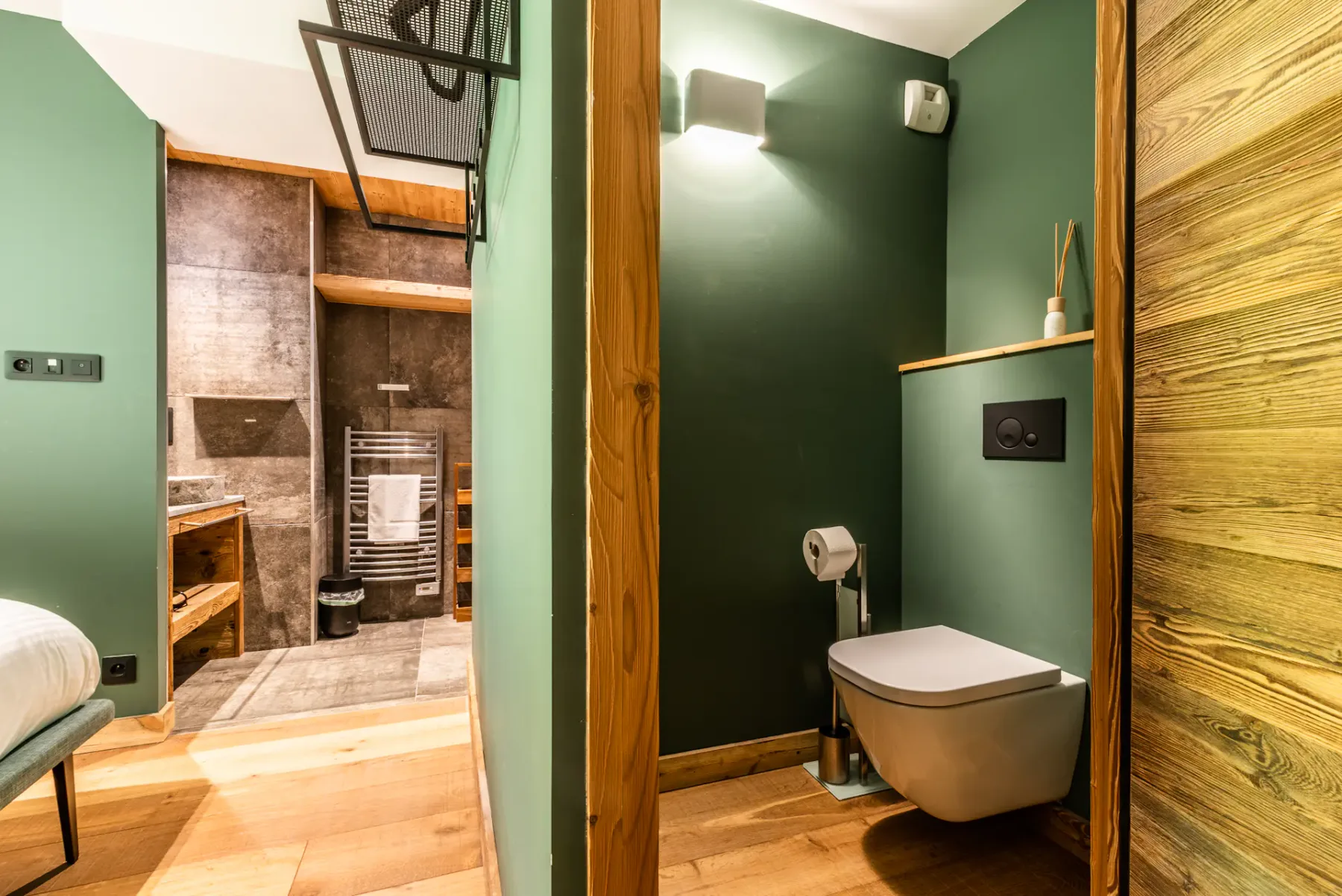 A bathroom with a wall-mounted toilet and an open shower area.