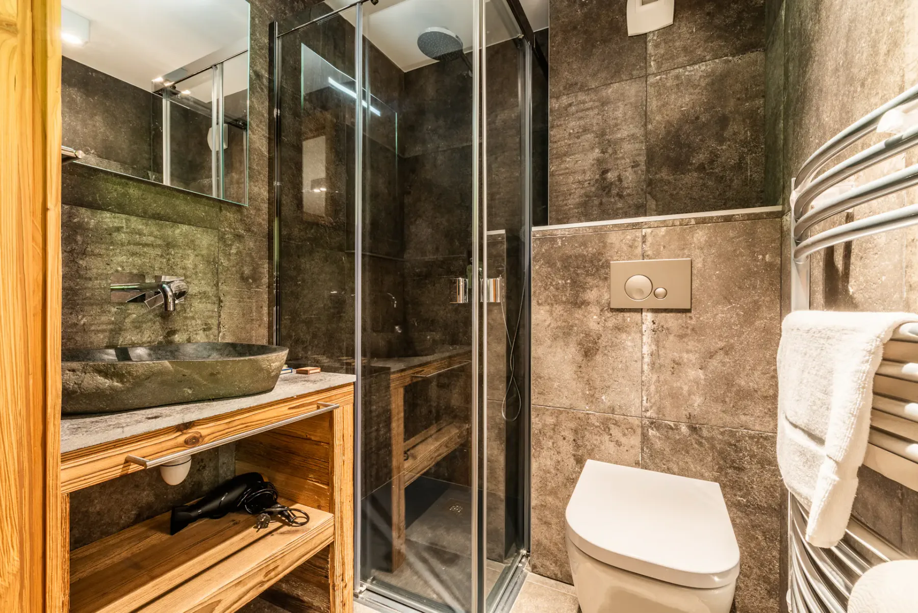 A tiled bathroom with a glass shower, sink, and toilet.