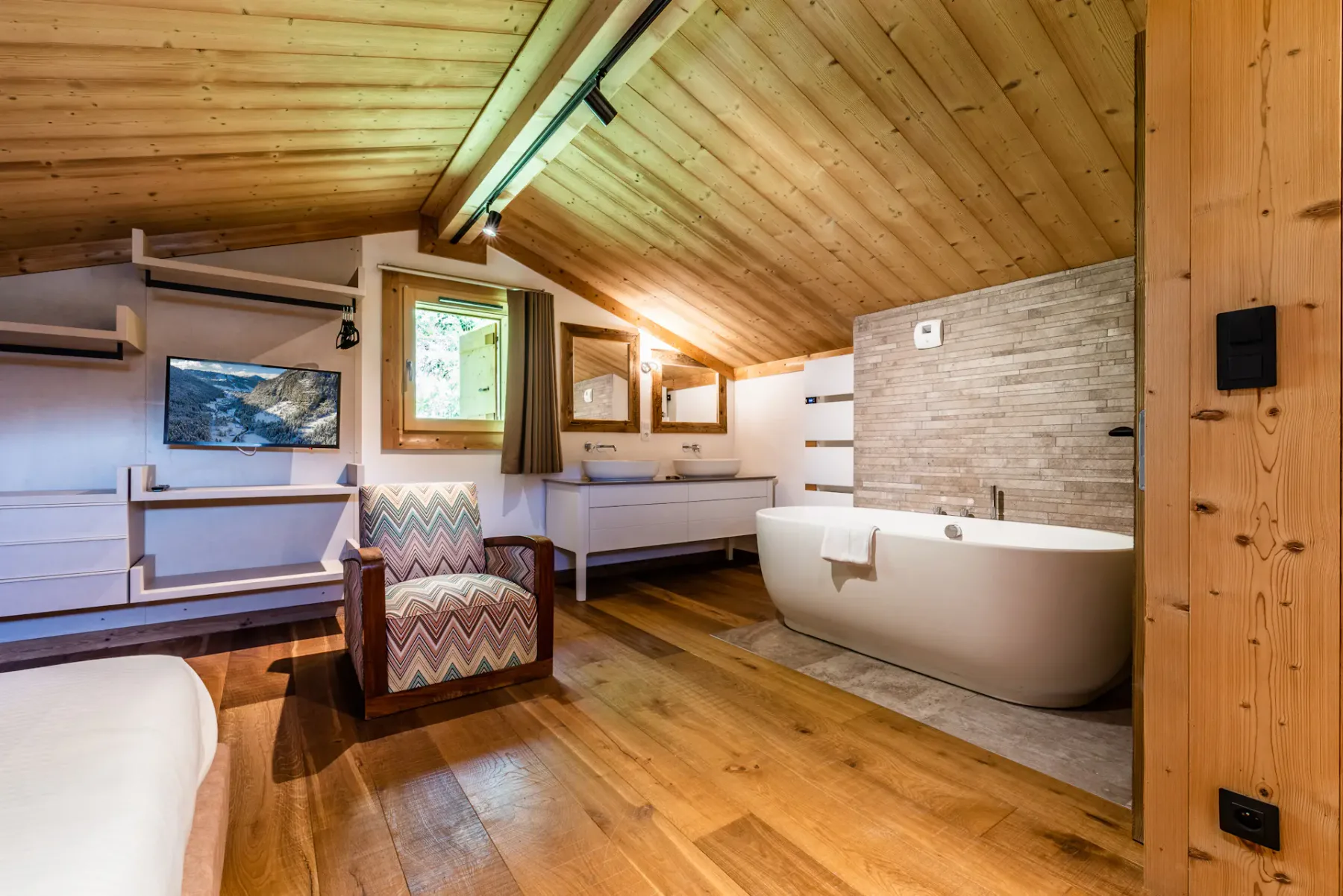A wood-paneled bedroom with a freestanding bathtub and seating area.