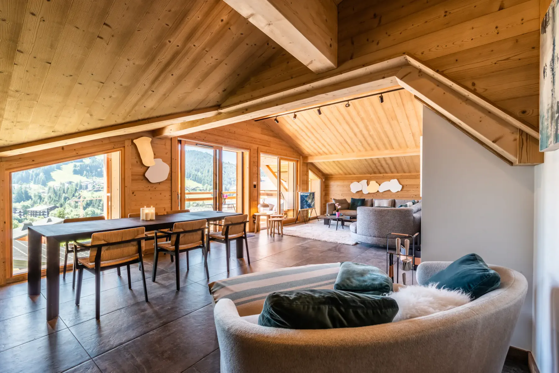 A bright living and dining area has a table beside large windows.
