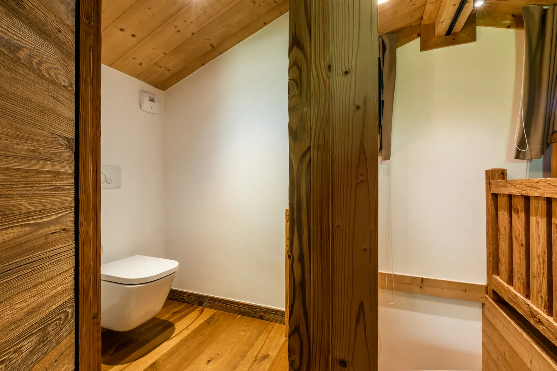 A wood-paneled bathroom with a wall-mounted toilet and shower.