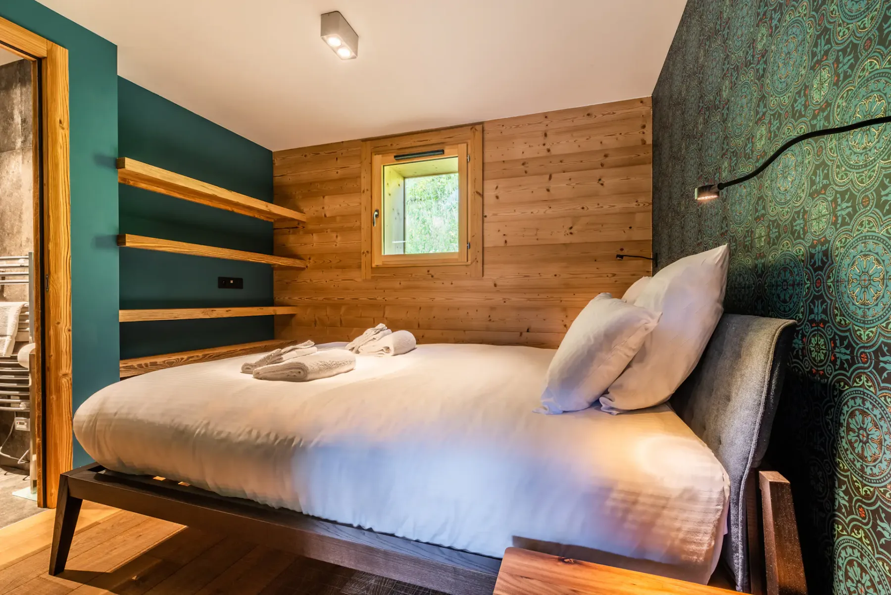 A bedroom with a double bed, wooden walls, and built-in shelves.