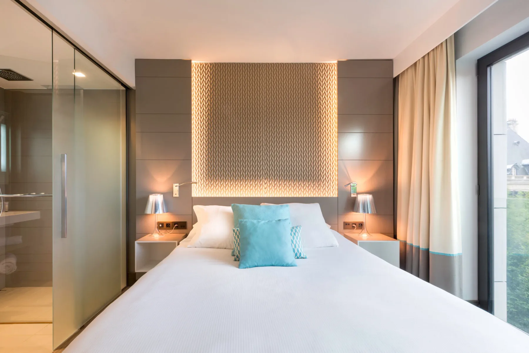 Una habitación de hotel con cama, un gran ventanal y un baño con ducha.