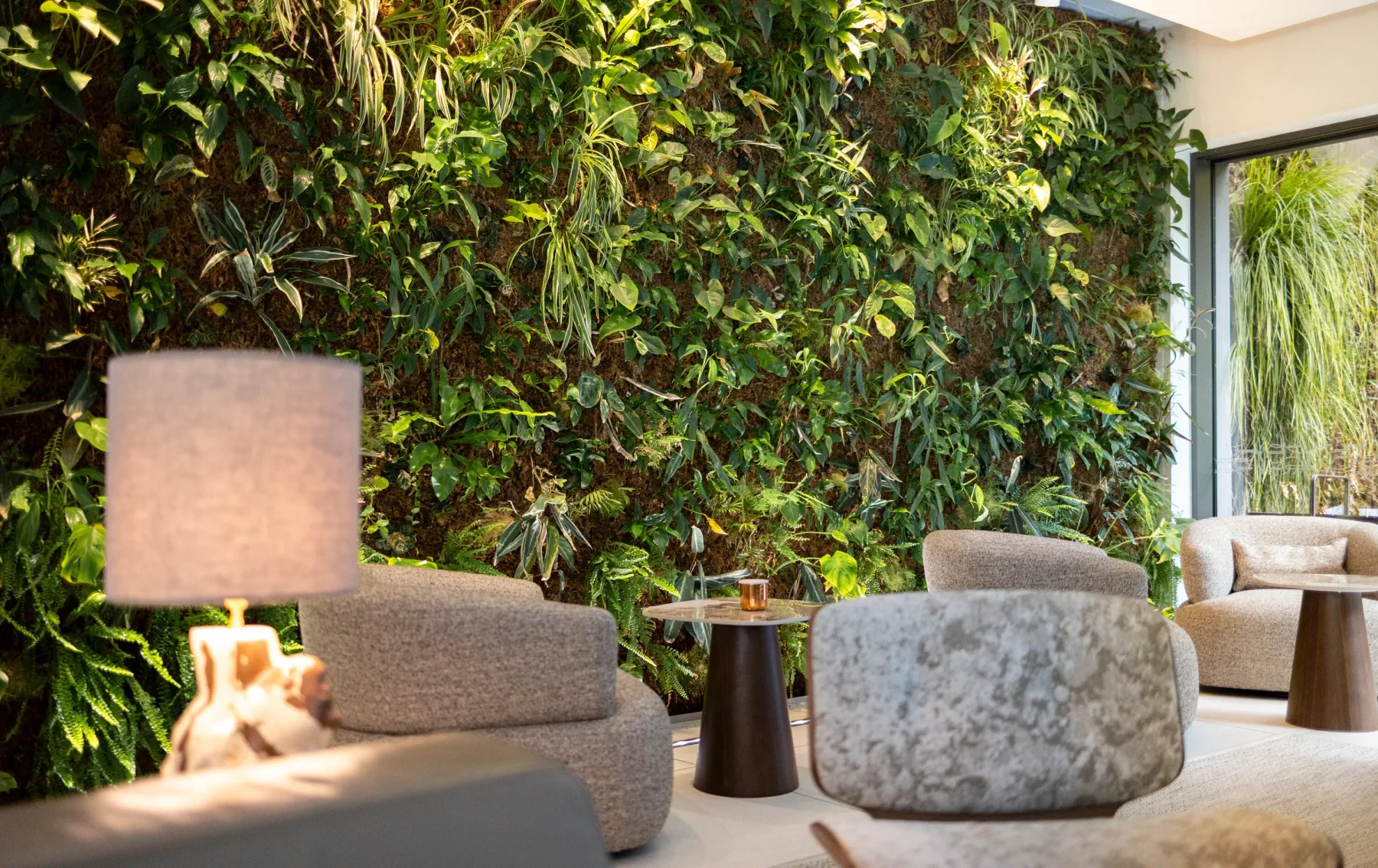 Zona de estar en el vestíbulo del hotel, con asientos y una pared vegetal decorativa.
