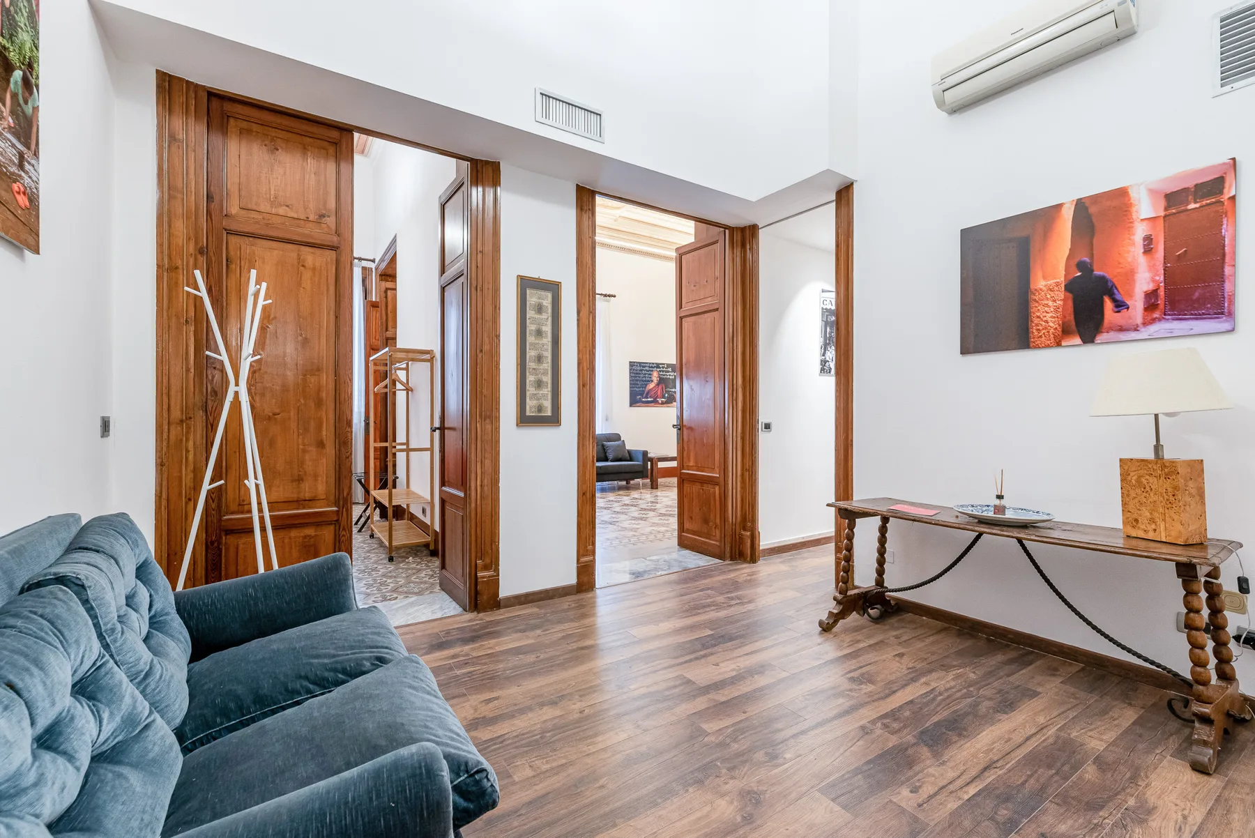 A bright living room with teal seating and open wooden doorways.