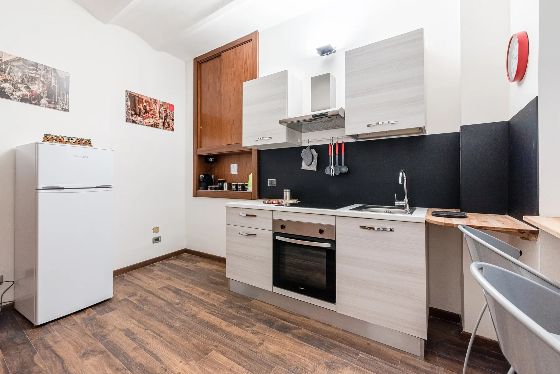 A modern kitchen with light cabinets, a refrigerator, and a built-in oven.