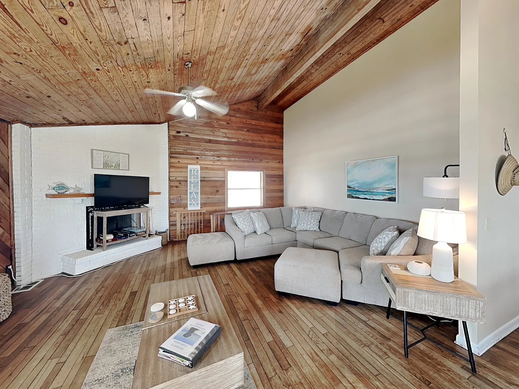 Living room with a sectional seating area, television, and wooden ceiling.