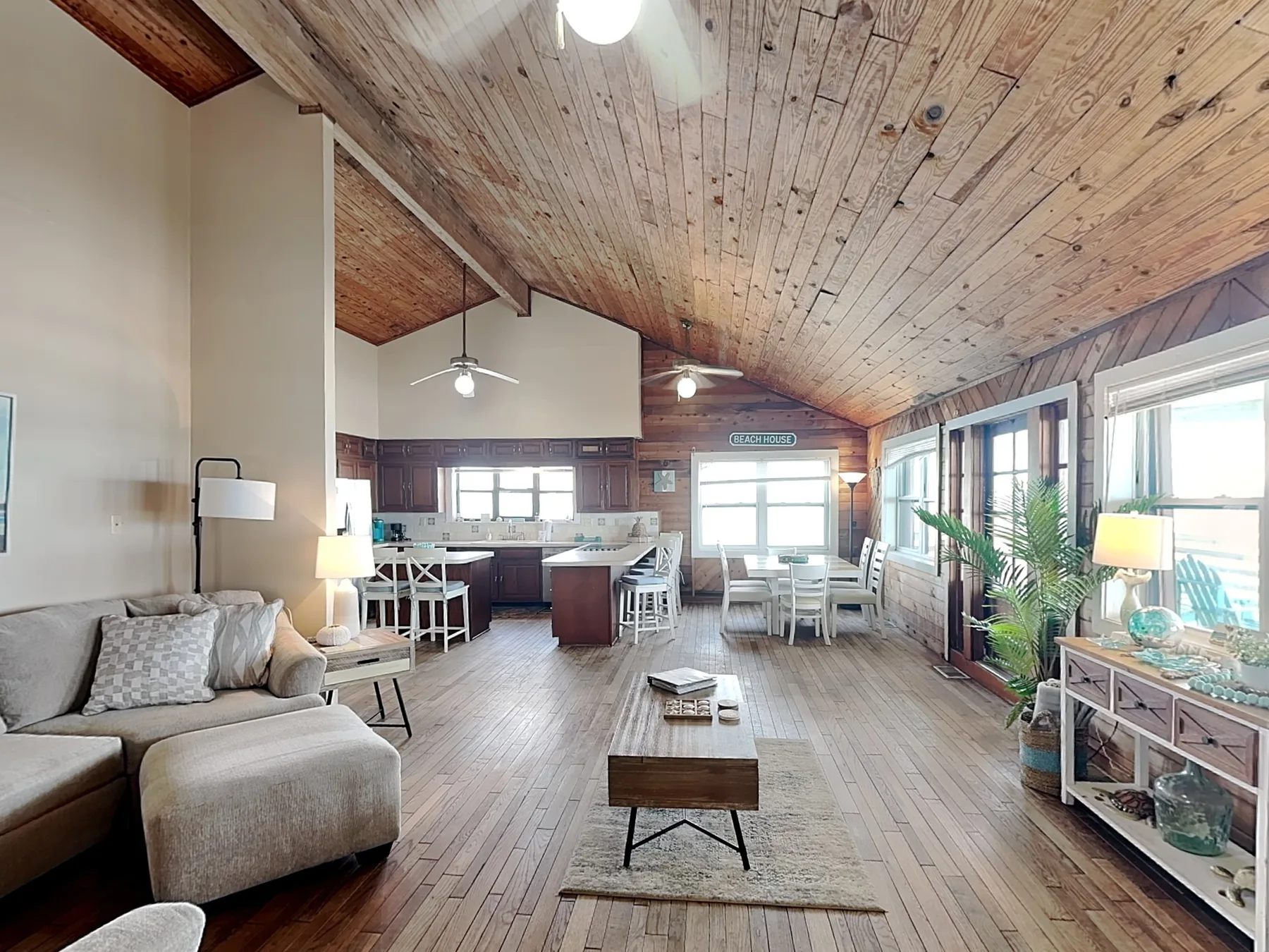 A bright living and dining area with wood ceilings and large windows.