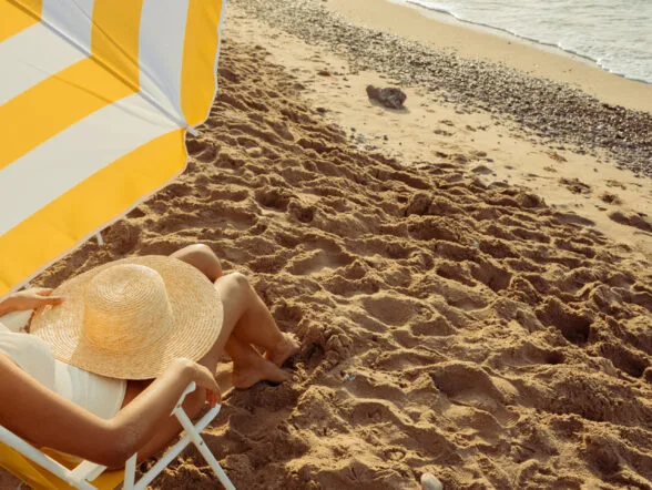 Persona descansando bajo una sombrilla de playa