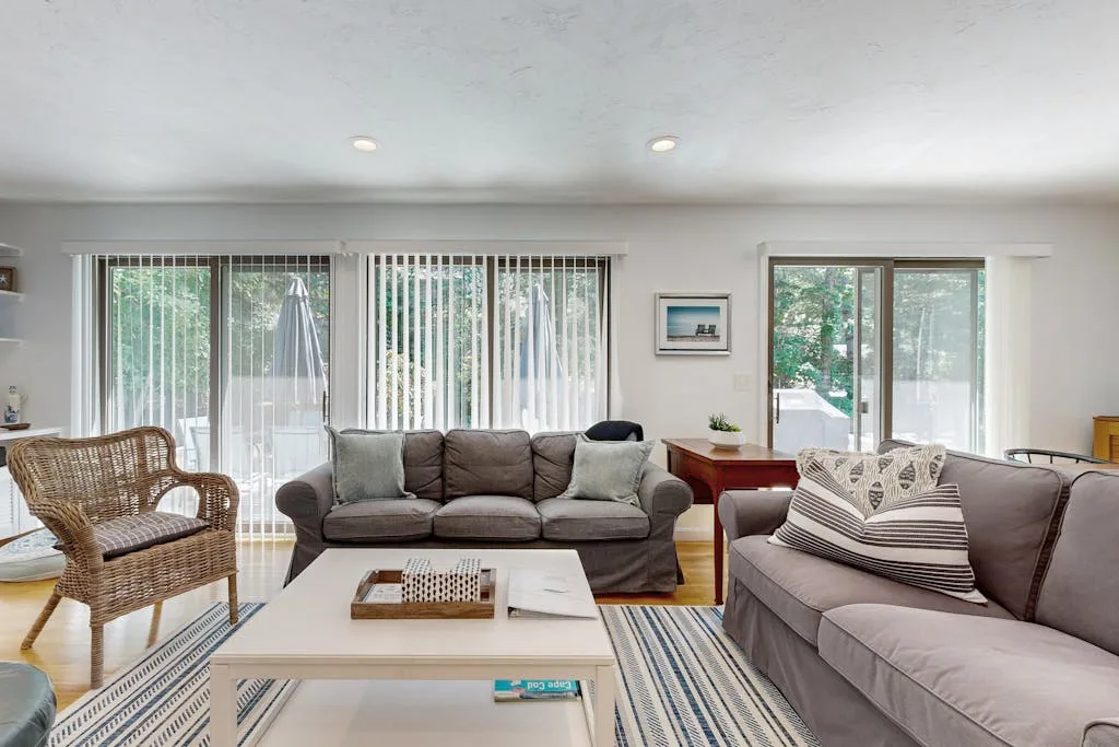 A bright living room with seating, a coffee table, and large windows.