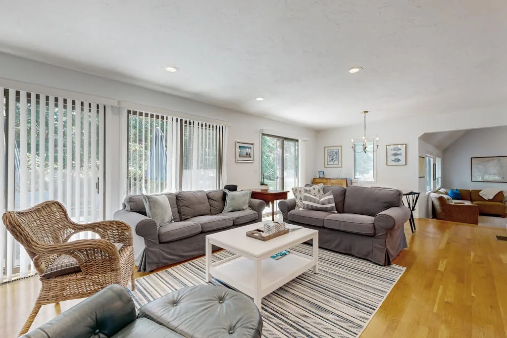 A bright living room with sofas, a coffee table, and large windows.