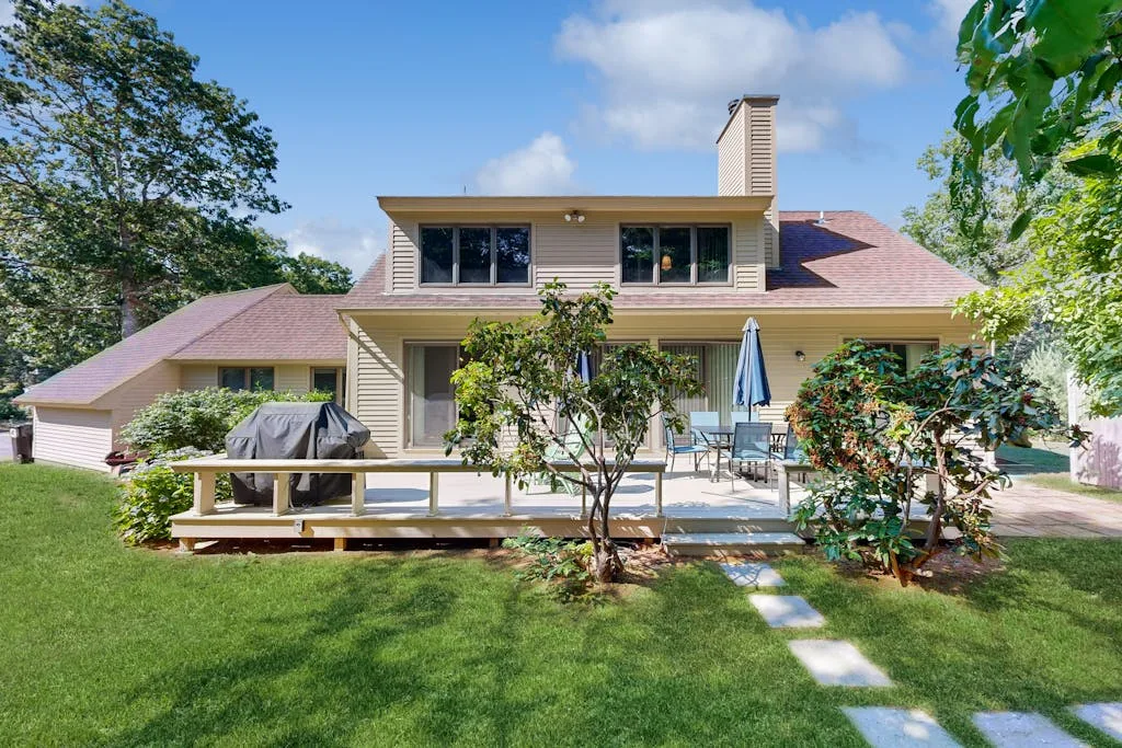 A house with a raised deck and green lawn.
