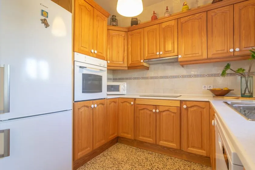 A warm-toned kitchen with wooden cabinets and built-in appliances.