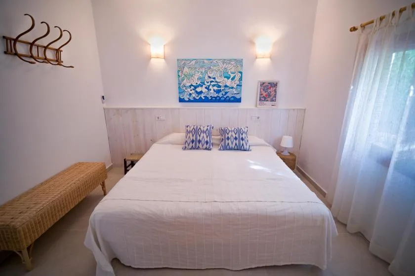A bedroom with a neatly made bed and colorful artwork above the headboard.