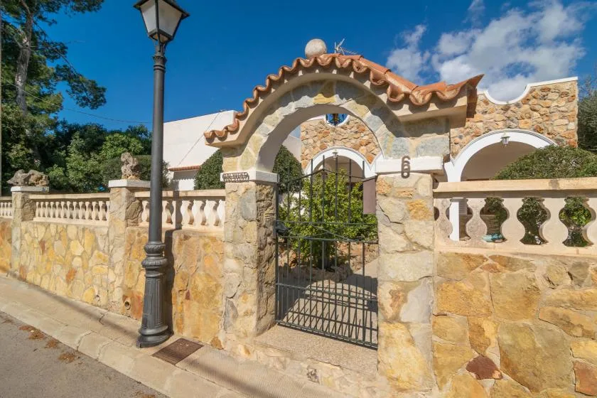 A stone entrance with a decorative arched gateway and closed metal gate.