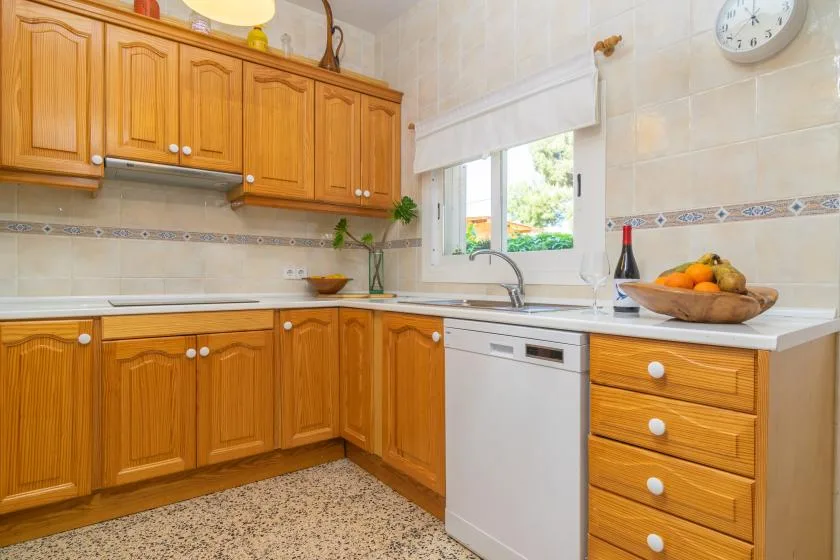 A bright kitchen with wooden cabinets, a sink, and a window.