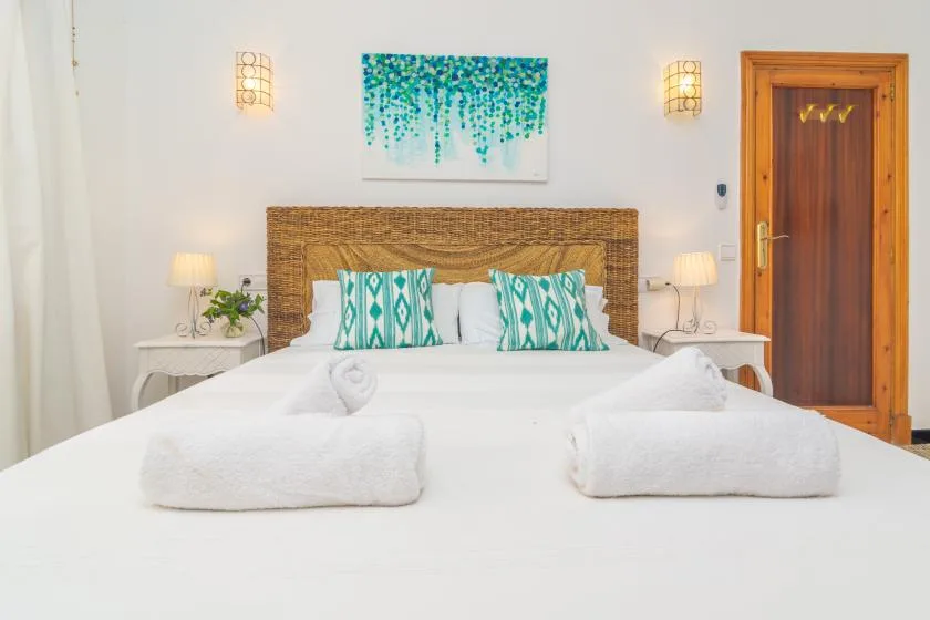 A bedroom with a neatly made bed, patterned pillows, and bedside tables.