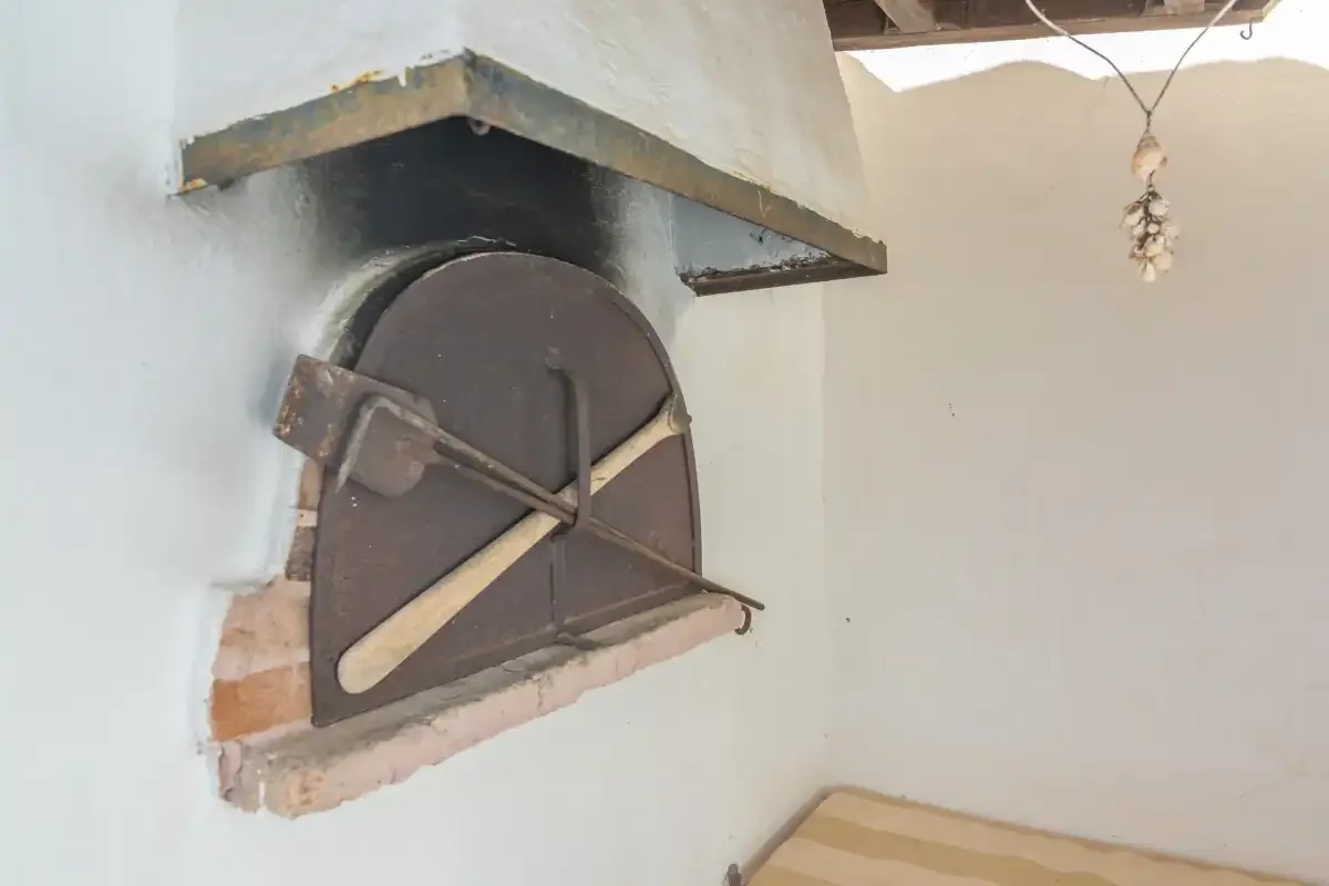 A built-in oven with a dark arched door is set into a white wall.