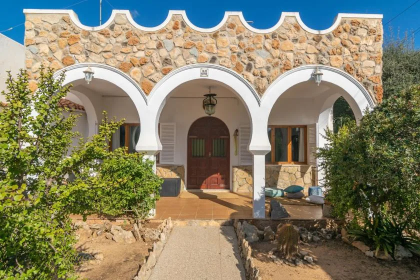 A stone building facade with three white arches and a central entrance.