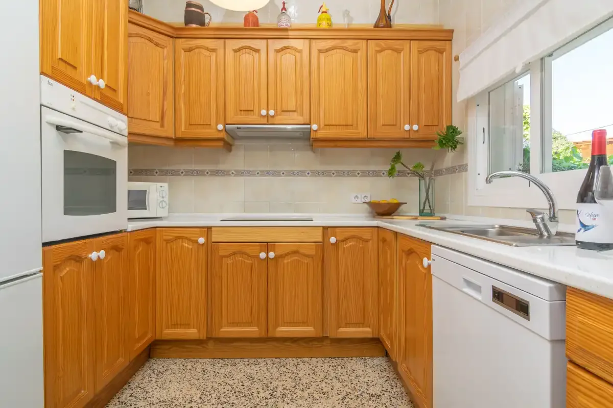 A kitchen with wooden cabinets, a countertop, and a sink by the window.
