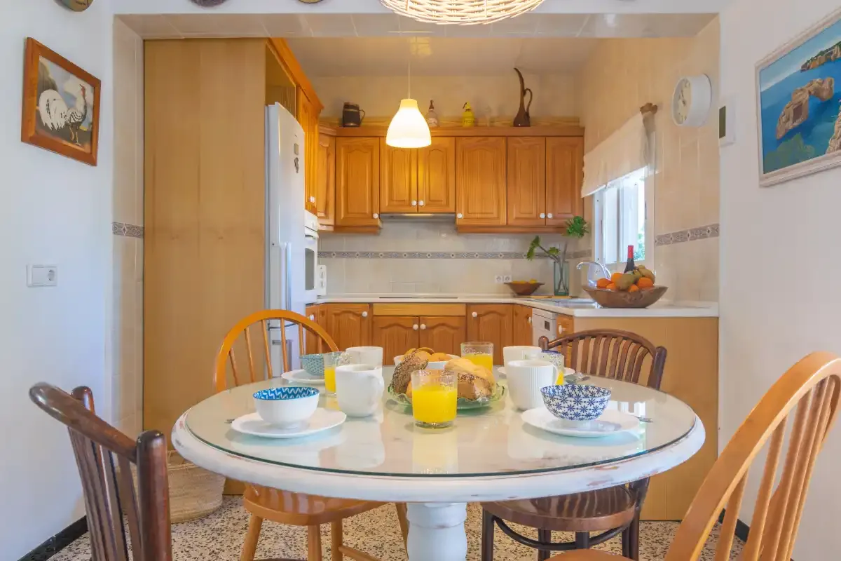 A dining area with a round table set in front of a wood-cabinet kitchen.