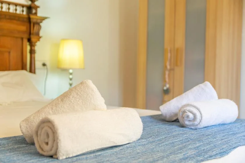 A bedroom with neatly arranged towels on a bed and a bedside lamp.