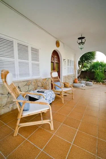 A covered patio with wicker seating, shuttered windows, and an arched doorway.