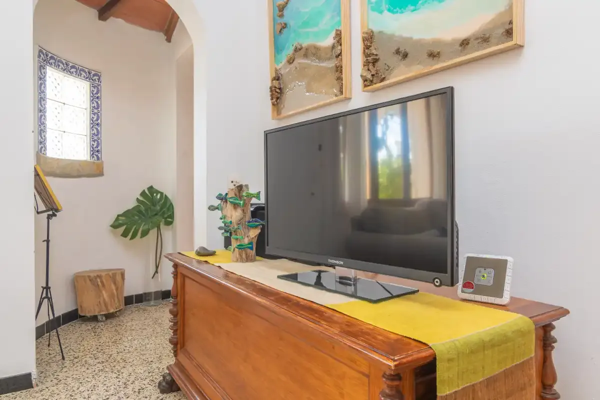 A living room with a television on a wooden cabinet and framed artwork.