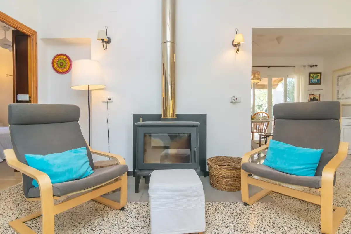A living room with two cushioned seats beside a wood-burning stove.