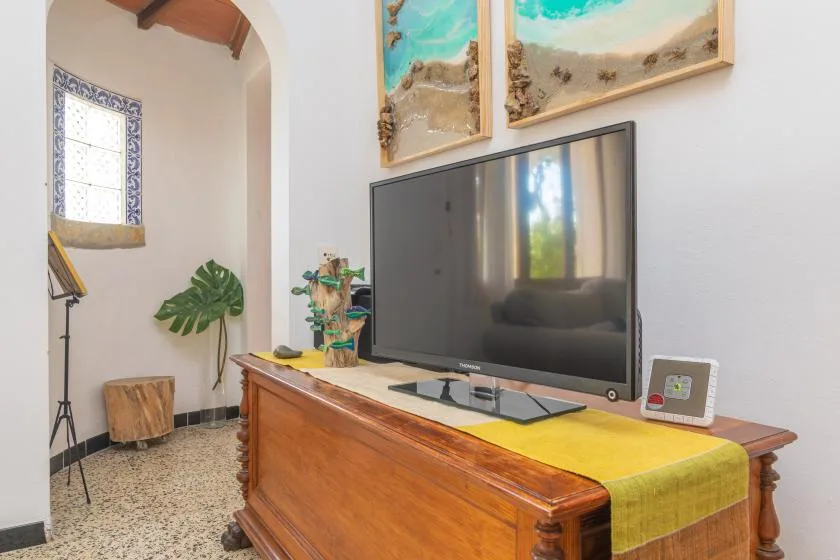 A living room with a television on a wooden console and colorful artwork above.