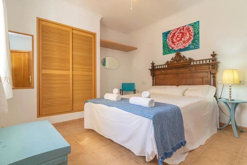 A bedroom with a large bed, wooden headboard, and colorful wall art.