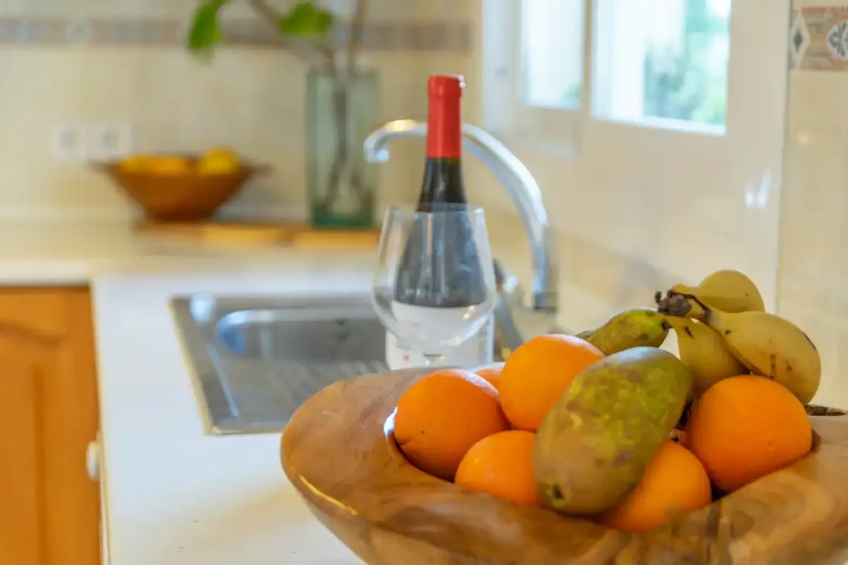A kitchen counter with a bowl of fruit beside the sink.