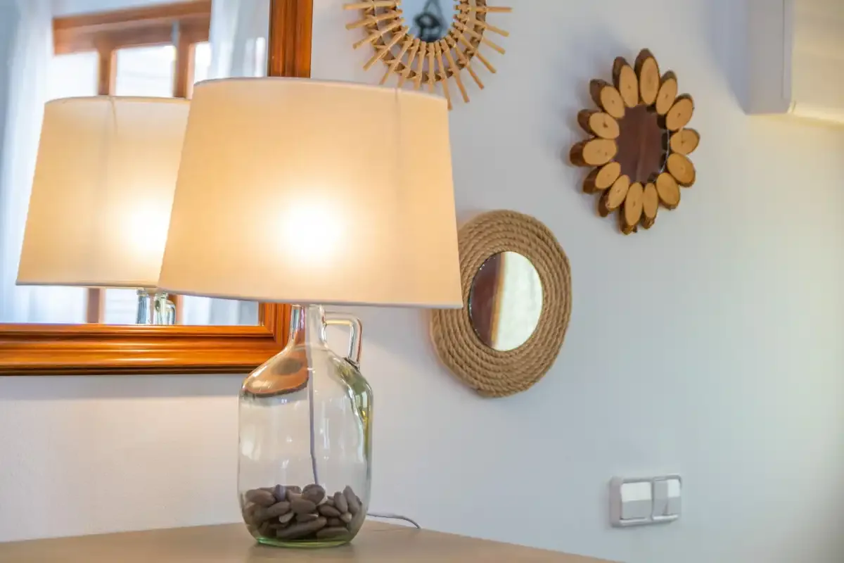 An interior tabletop scene features a lit lamp beside decorative mirrors.