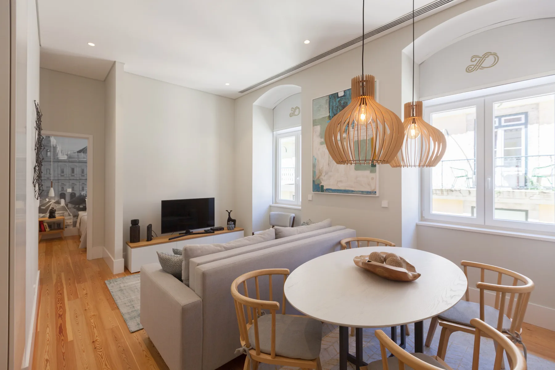 A bright living and dining area with seating, a round table, and large windows.