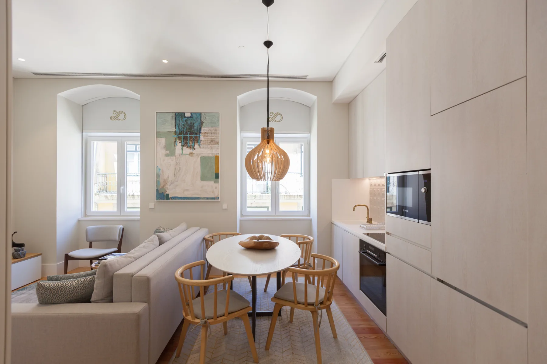 A bright living and dining area with a table, seating, and kitchen cabinets.