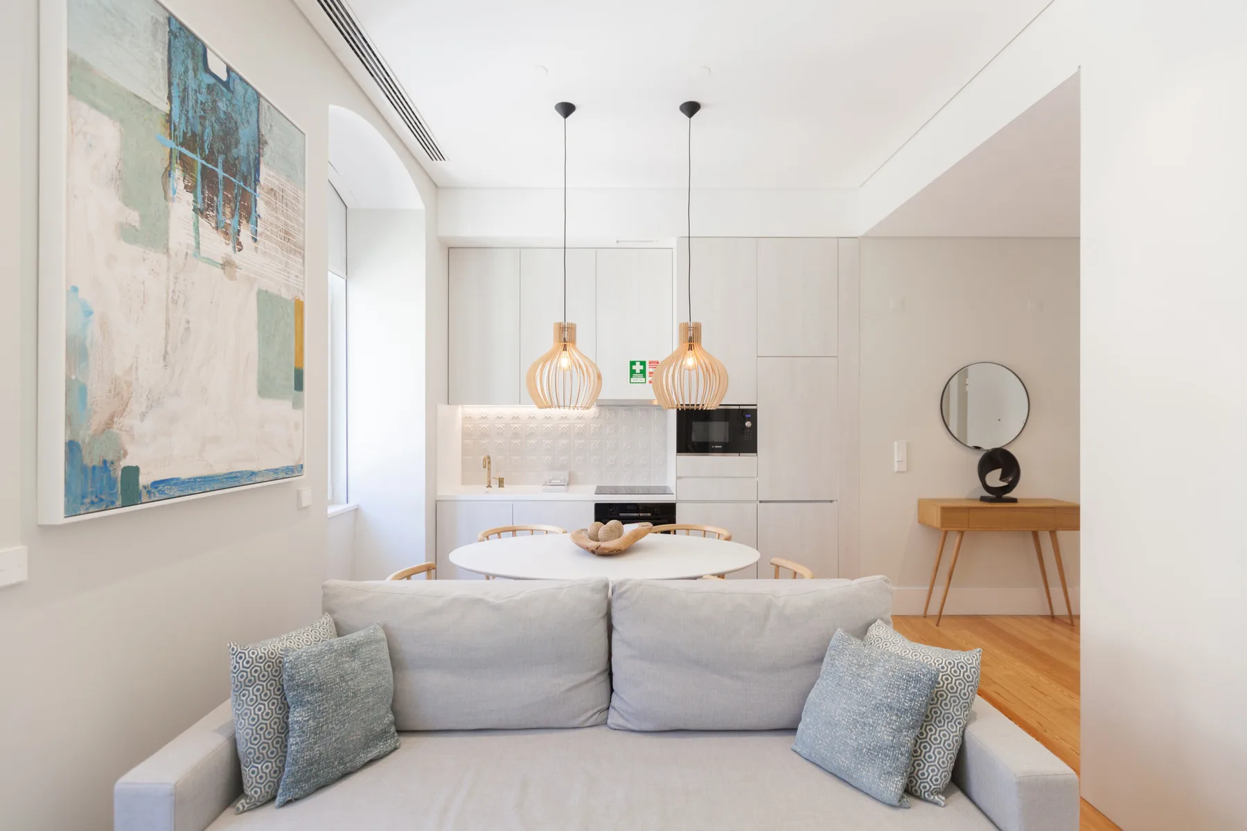 A bright living and dining area with a sofa, table, and compact kitchen.