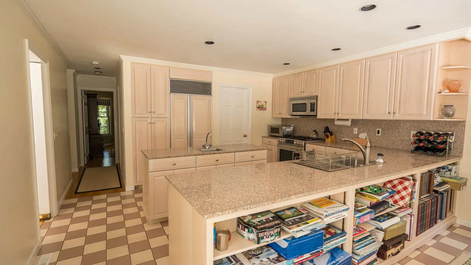 Una cocina luminosa con gabinetes claros y una isla grande con estantes abiertos.