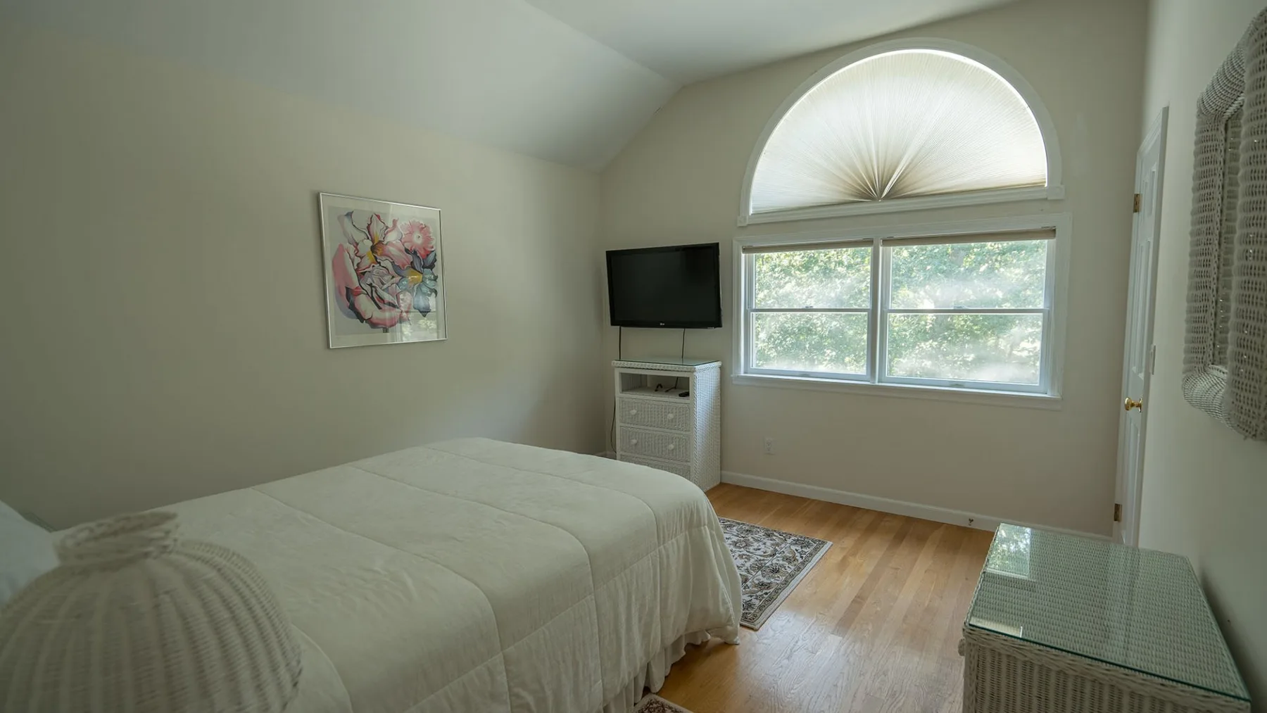 Un dormitorio con una cama, un televisor y una gran ventana arqueada.