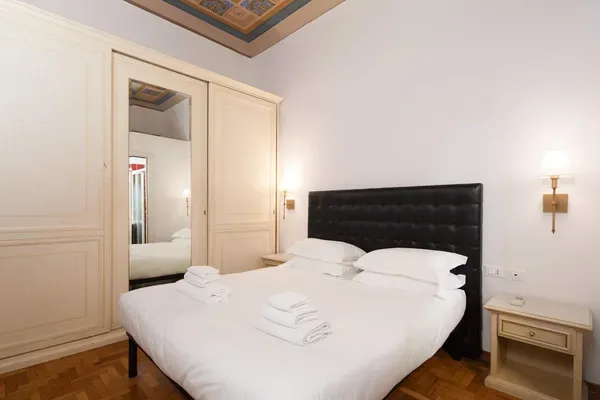 A bedroom with a neatly made bed and a mirrored wardrobe.