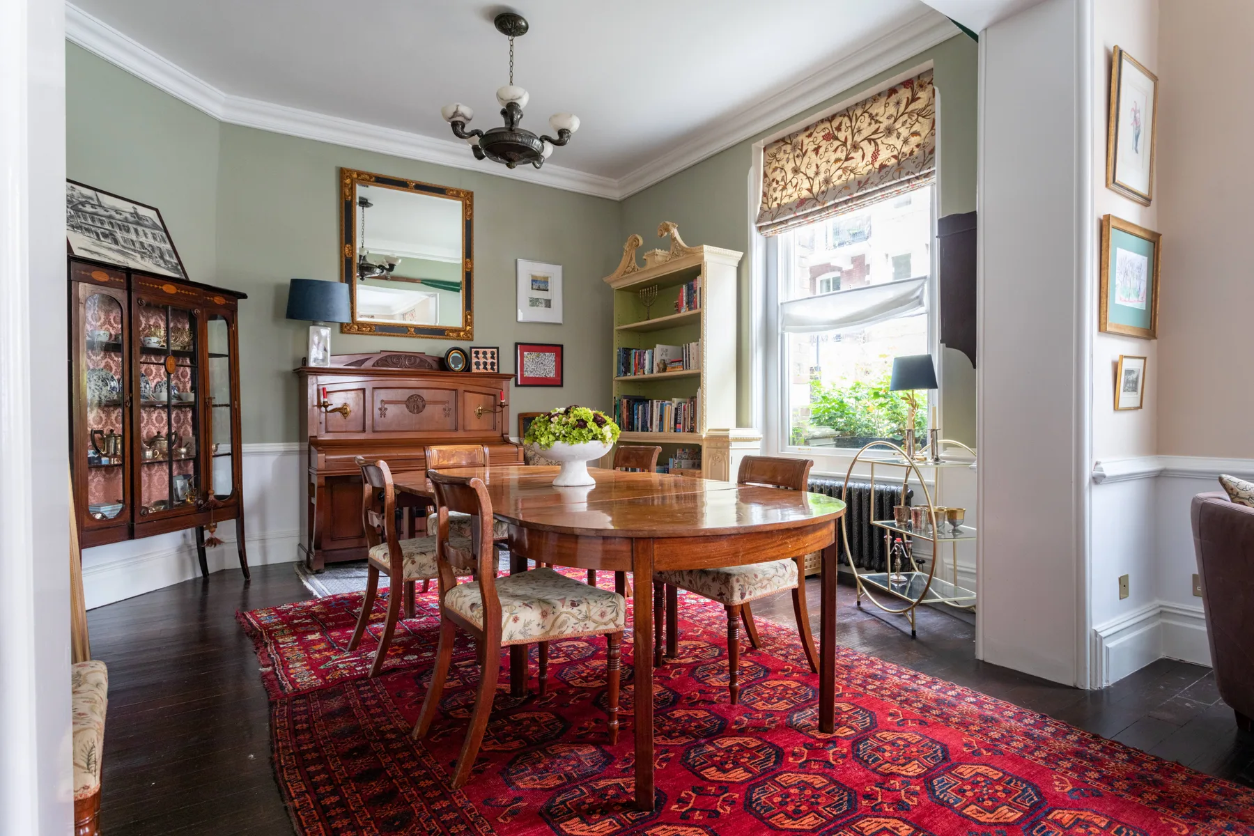 A dining room with a wooden table, chairs, and a patterned rug.