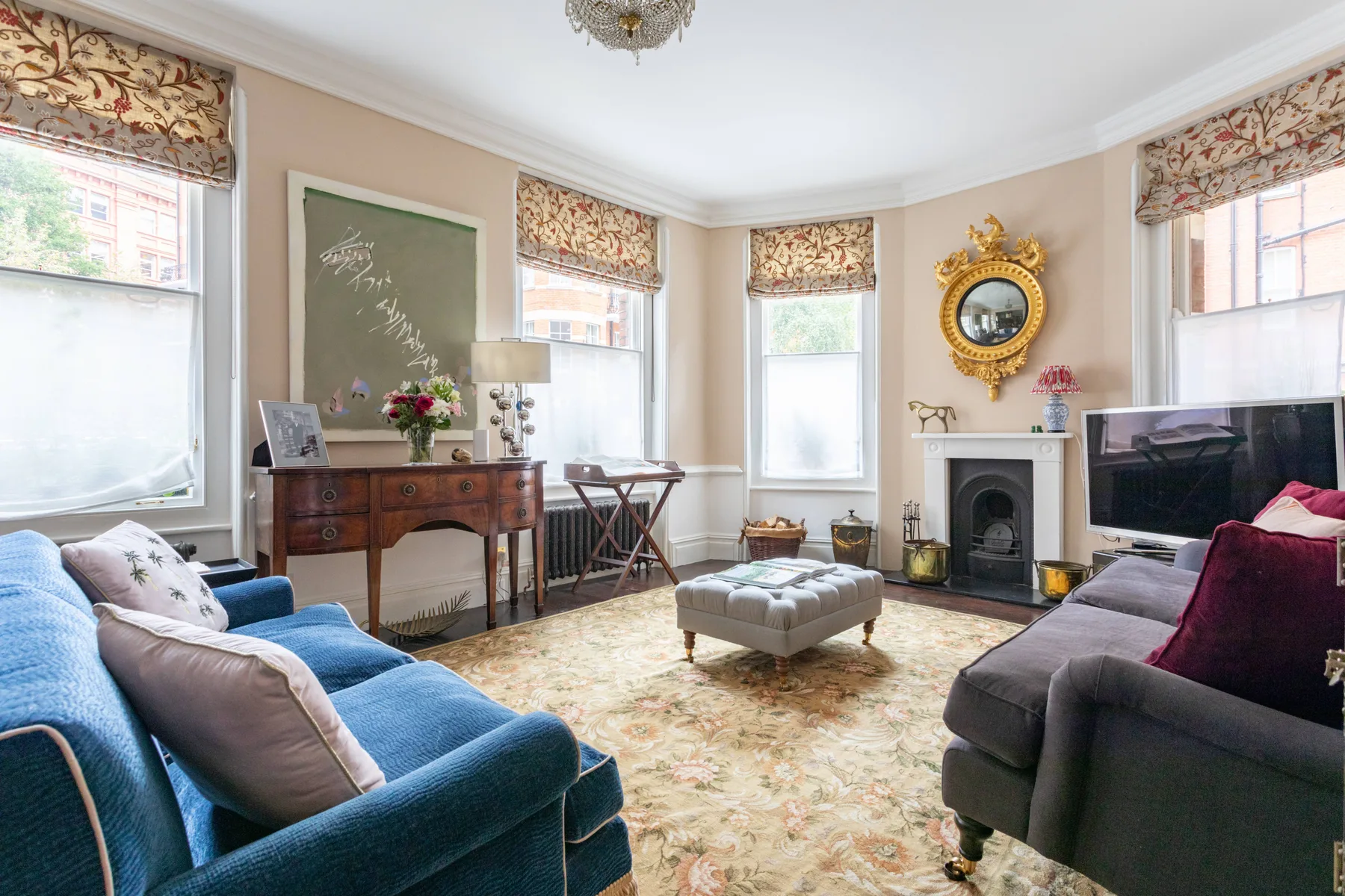 A living room with sofas, a fireplace, and tall windows.
