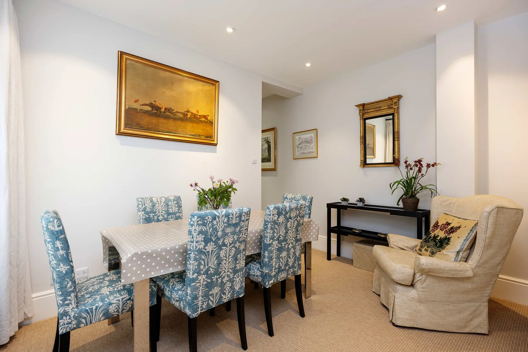 A dining area with a table and blue patterned seating beside a sitting area.