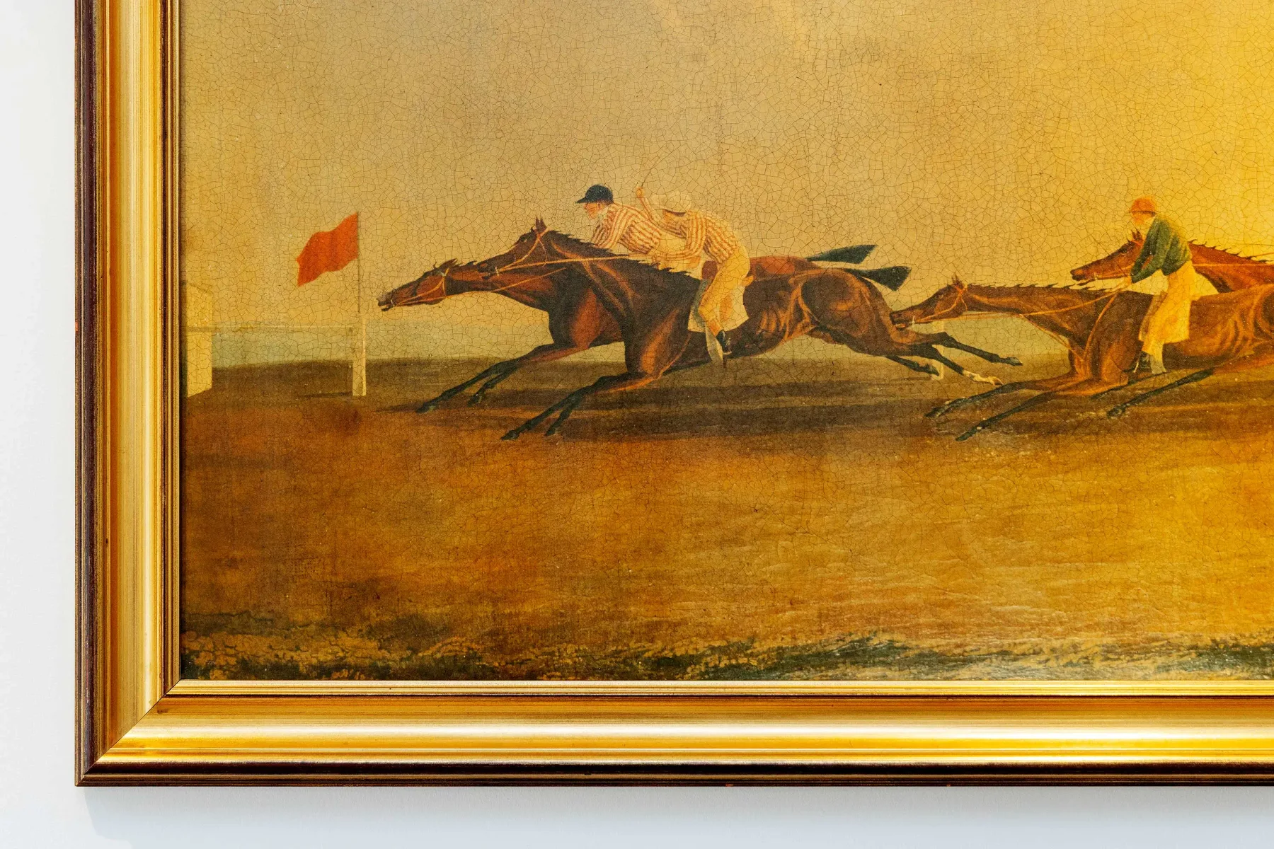 A framed painting shows riders racing horses across an open field.