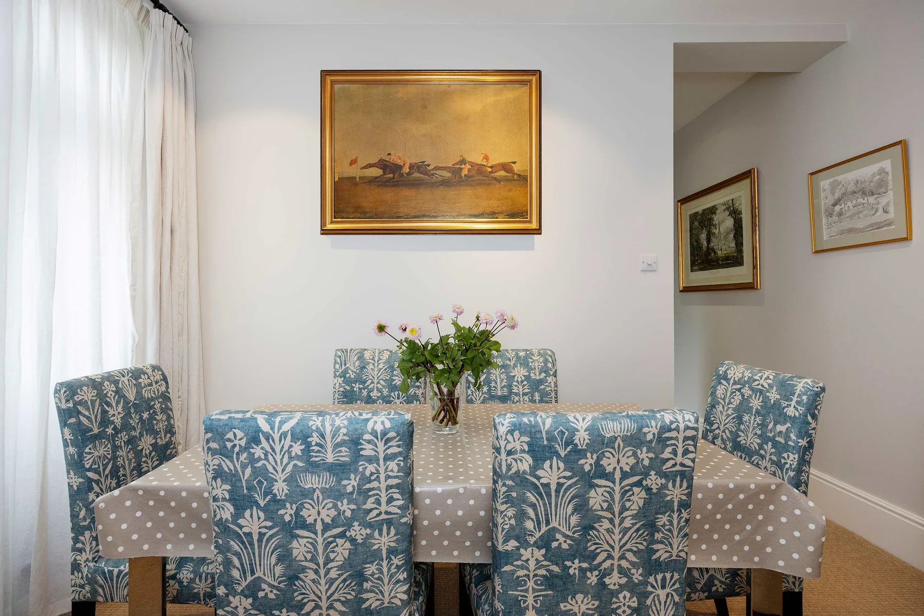 A dining area with a patterned tablecloth and floral upholstered seating.