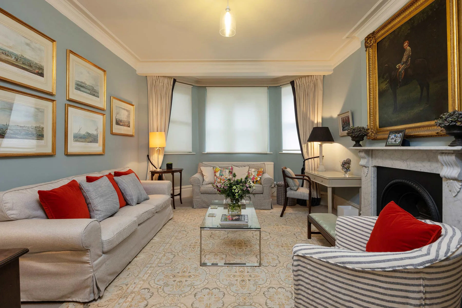A formal living room with sofas, framed artwork, and a fireplace.